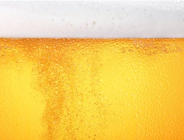 Buzlu bardaktaki köpüklü lager birasının arka plan dokusunu kapatın. Düşük açılı, kenarlı, köpüklü.