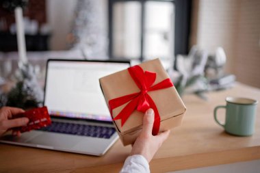 Yetişkin bir adamın dizüstü bilgisayarında tatil öncesi hediyesi var. İnternetten alışveriş yapıyor. Mutlu yıllar ve mutlu Noeller.