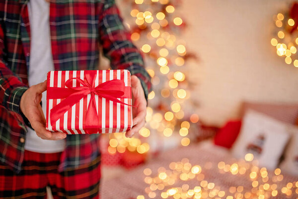 Adult man holds in his hand a box with a gift for Advent holiday. Happy New Year and Merry Christmas