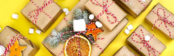 Many craft gift boxes on yellow background. Christmas holiday package banner. New year knolling flat lay still lfe — Stock Photo, Image