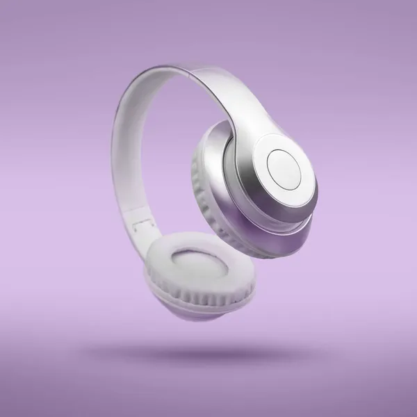 Срібні металеві білі бездротові навушники в повітрі на фіолетовому тлі Лавендули. Музичний прилад левітаційна концепція — стокове фото
