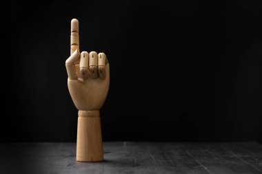 Ahşap bir el resmi, siyah izole edilmiş arka planda, ahşap bir masanın üzerine yerleştirilmiş.