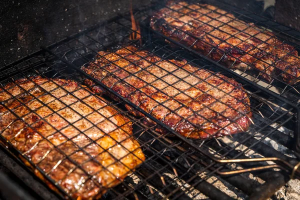 Foco seletivo de bifes de carne suculentos grelhados na grelha de churrasco com fumaça — Fotografia de Stock