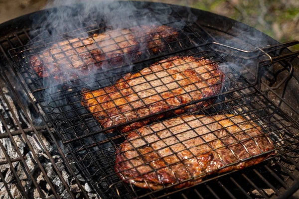 Foco seletivo de bifes de carne suculentos grelhados na grelha de churrasco com fumaça — Fotografia de Stock