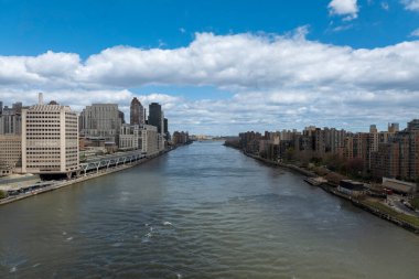 Nehir kanalındaki New York City gökdelenleri, bulutlu ve mavi gökyüzü arka planı
