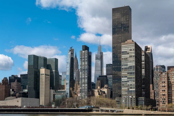 Nehir kanalındaki New York City gökdelenleri bulutlu ve mavi bir arka plana sahiptir. Yüksek kaliteli fotoğraf.