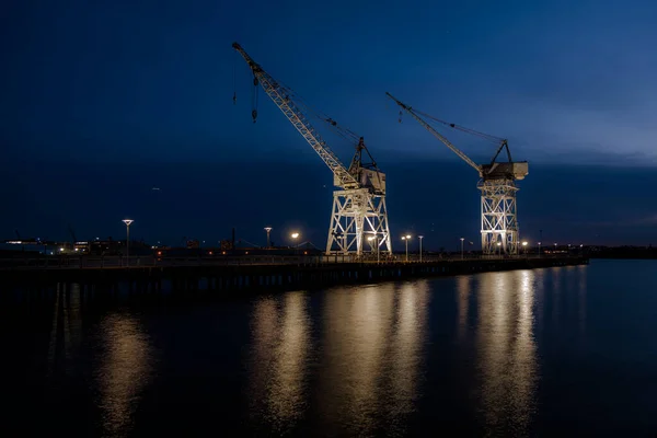 old port cranes at night with reflection in the water. High-quality photo