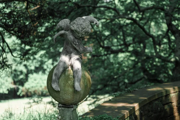 Ceramic sculpture of a little sitting Angel in a New Jersey Botanical Garden. High-quality photo