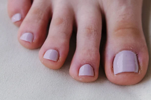 Close-up of female feet painted grey nail polish, self made pedicure at home. High-quality photo