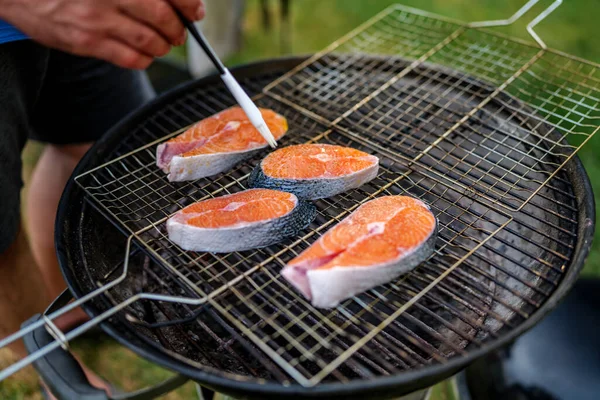 Close up of oiled fresh salmon steak prepared for grilling with grains of salt on it, lies on grill mesh . High-quality photo