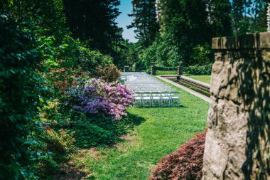 White Wedding Chairs Lined Up before a Real Life Outdoor Summer Wedding In New Jersey Botanical Garden Alley . Hight-quality photo
