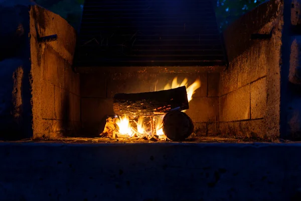 Brick Fireplace in garden. Design Street Fireplace and built by brick at backyard at home. Concrete stone fireplace to ignite the wood. The view of a backyard fireplace with burning logs and beautiful