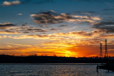 High voltage electricity tower sky sunset landscape, industrial background with water lake on front. High-quality photo