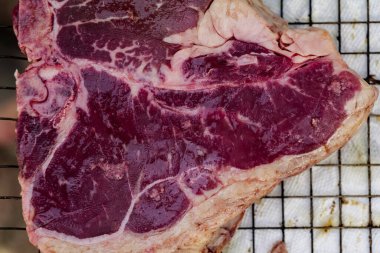 Close up of Fresh cut, raw T-bone steak prepared for cooking on the grill