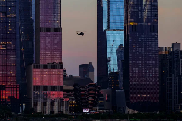 View to Manhattan skyline Hudson Yards skyscrapers and helicopter on the front, from Weehawken Waterfront in Hudson River at sunset. High quality photo