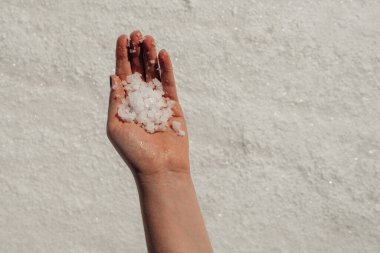 Kadın elinin içinde bir avuç tuz, arka planda tuz. Yüksek kaliteli fotoğraf.