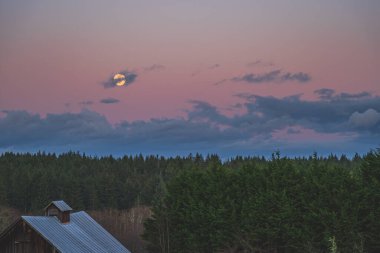 İlçe sahnesinde yükselen sarı aylı dramatik akşam gökyüzü 