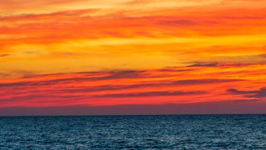 Canlı turuncu günbatımı gökyüzü ve okyanus üzerindeki bulutlar