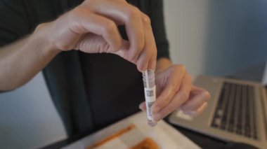Kadının ellerinin kapalı görüntüsü PCR test numunesini test tüpüne yerleştiriyor.