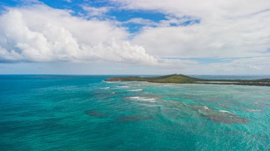 High angle view of Reserva Natural Cabezas de San Juan in Fajardo, Puerto Rico. Faro Las Cabezas de San Juan lighthouse of the heads of San Juan sits on the hill. blue water and puffy clouds, 