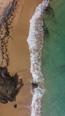 A vertical overhead shot of Colora beach with crashing waves in Puerto Rico