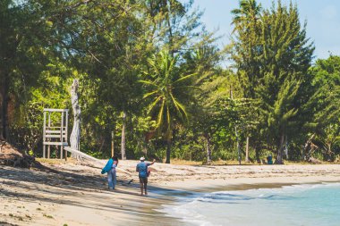 A Couple walking along deserted tropical beach in the Caribbean on summer day