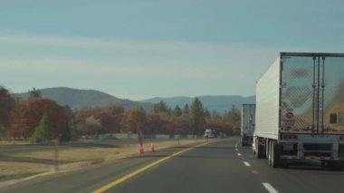 Oregon 7 Kasım 2019: Sabahın erken saatlerinde Oregon kırsalında otobanda traktör römorklarının önünden geçmek.