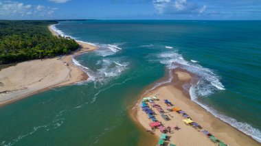 Aerial view of Caraiva beach, Porto Seguro, Bahia, Brazil. Colorful beach tents, sea and river.
