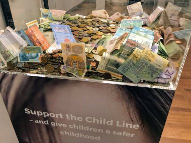 Kopenhag havalimanında daha iyi bir çocukluk fonu için para ve banknotlar içeren şeffaf bağış kutusu