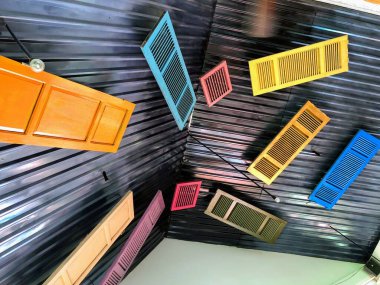 Misafir odasının metal siyah tavanından sarkan farklı renk kapıların kurulumu