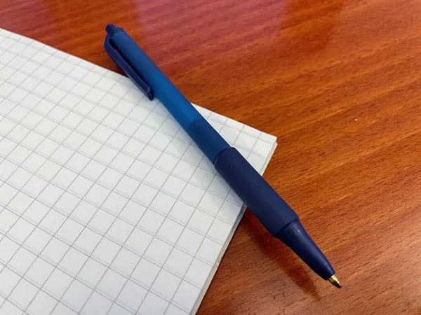 Μπλε Στυλό Στο Λευκό Χαρτί Πλέγματος Στο Ξύλινο Καφέ Γραφείο — Φωτογραφία Αρχείου