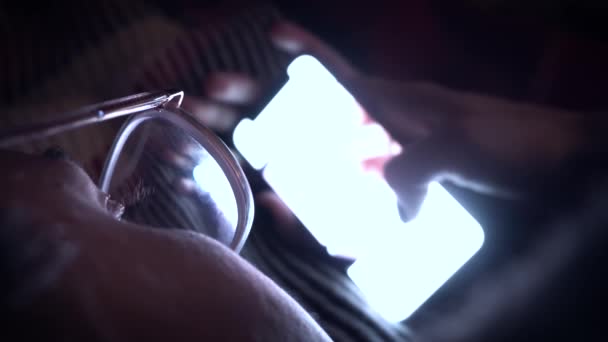 Dívka procházení sociálních médií na svém telefonu, zatímco leží na posteli. Noc. close-up. — Stock video
