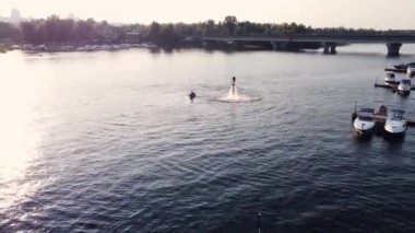 Genç adam rıhtımın yanında uçan bir kaykaya biniyor. Eğitim. Gün batımı. Drone görünümü.