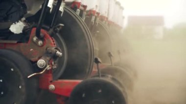 Tarlaya mısır tohumları ekiyor. Traktör bir ekiciyle tarlada çalışıyor..