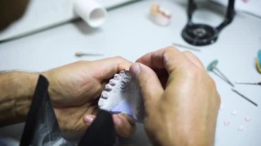 Diş teknisyeni atölyesinde çalışıyor ve dişçilik için yapay diş yapıyor. yakın plan.