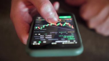 İşadamı, cep telefonu ekranındaki dijital bir değiş tokuşun fiyat tablosunu kontrol ediyor. yakın plan.