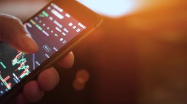 Cep telefonlu eller. Şifreli akıllı telefon ticareti. Yakın plan. Kripto para ticareti. Güneş ışınları