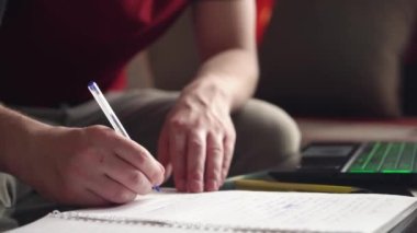 Genç adam evde bilgisayar kullanarak uzaktan öğrenme yapıyor. Koronavirüs izolasyonu. yakın plan