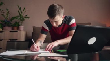 Genç adam evden çalışıyor. Uzaktan çalışma. Evrak dolduruyorum..