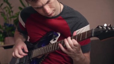 Genç adam dizüstü bilgisayarla elektronik gitar çalmayı öğreniyor. yakın plan