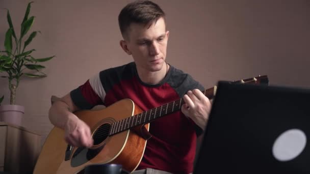 남자가 어쿠스틱 기타를 연주하기 배우고 있습니다 온라인 — 비디오