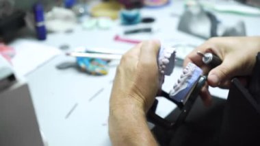 Diş teknisyeni atölyesinde çalışıyor ve dişçilik için yapay diş yapıyor. Laboratuvar. yakın plan.