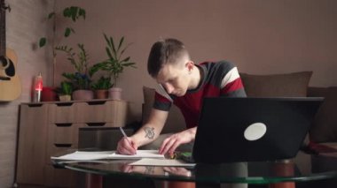 Genç adam evde çalışıyor. Uzaktan öğrenme. Rahat oda