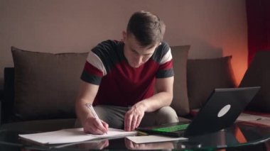 Genç adam evde çalışıyor. dokümanları doldurun.