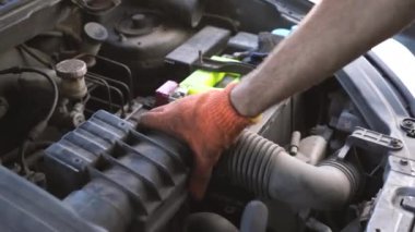 Otomatik tamirci arabadaki hava filtresini değiştiriyor.