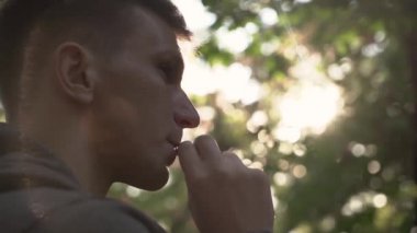 Genç adam şehir parkında sigara içiyor. Portre. gün batımı.