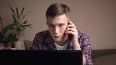Genç adam iş yerinde cep telefonuyla konuşuyor. Konforlu ev ortamı. yakın plan.