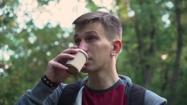 Joven Está Caminando Por Parque Con Una Taza Café Puesta — Vídeos de Stock