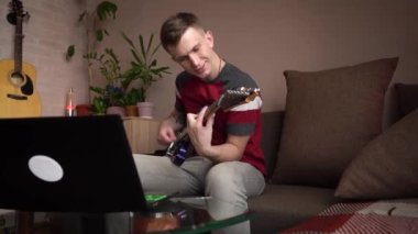 Genç adam bilgisayarla elektronik gitar çalmayı öğreniyor..