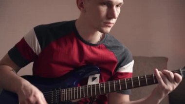 Mutlu genç adam evde elektro gitar çalıyor..
